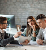 Young couple using digital tablet with their insurance agent during consultations in the office.
