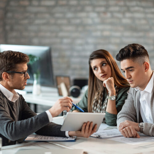 Young couple using digital tablet with their insurance agent during consultations in the office.