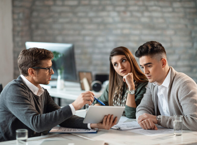 Financial advisor and young couple using touchpad on a meeting. Young couple using digital tablet with their insurance agent during consultations in the office.